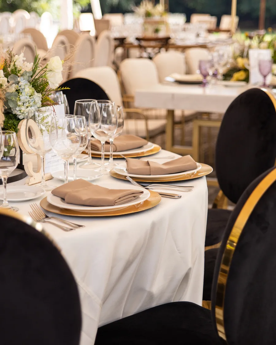 Montaje elegante de evento corporativo por AP Eventos con sillas en negro y oro y plato base dorado